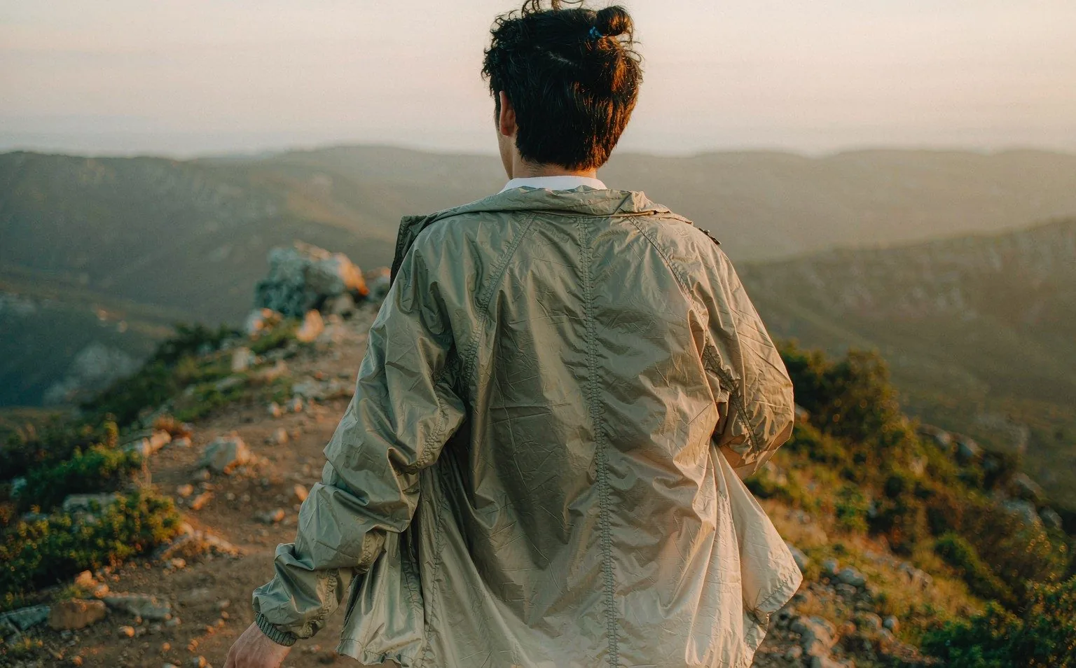Hiker in a packable 3L hardshell jacket on a mountain ridge